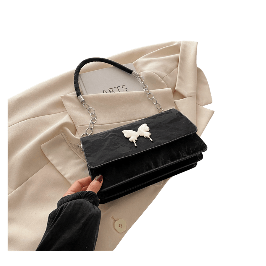 Black ladies handbag with decorative butterfly and magnetic snap closure