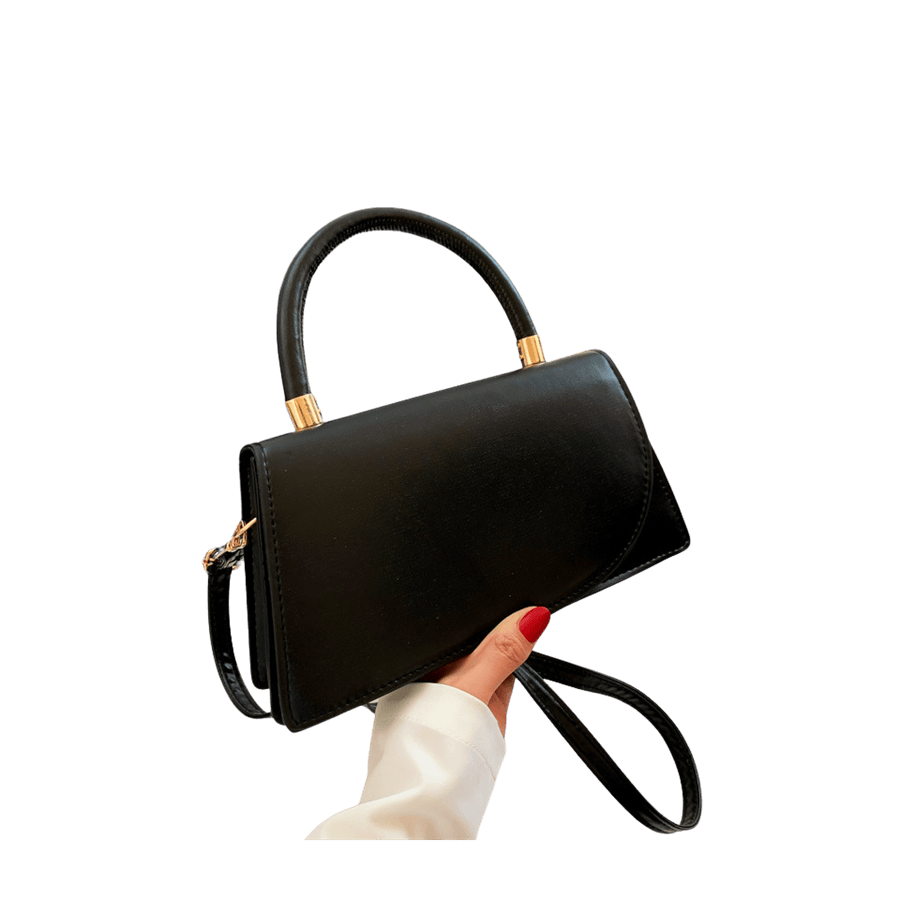 Black ladies handbag with decorative hardware on the handle and magnetic snap closure