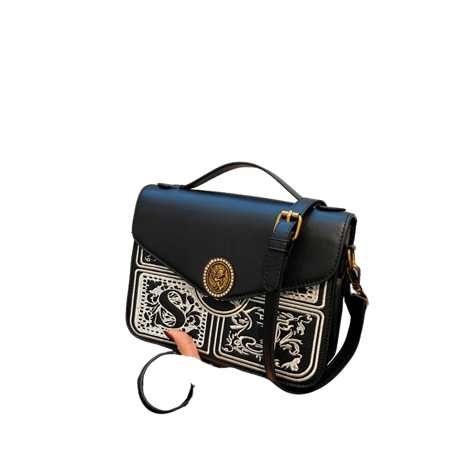 Black ladies handbag with embroidery on the front and round hardware on the flap