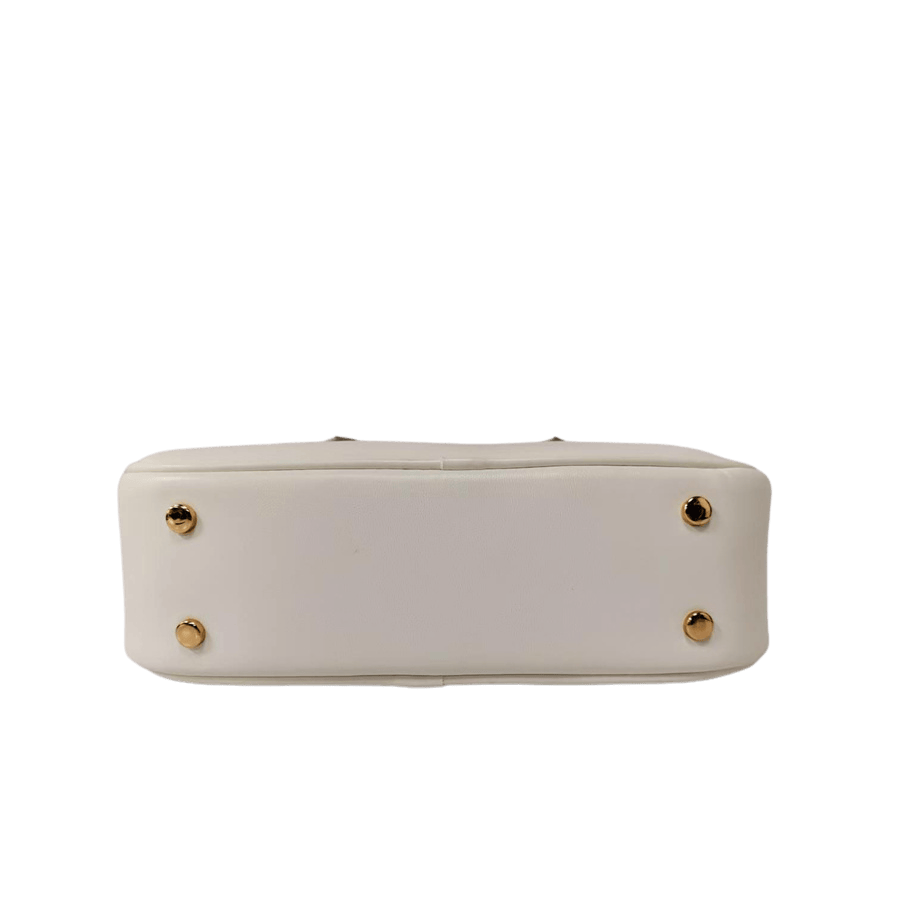 White ladies handbag with metal feets and piping around the body