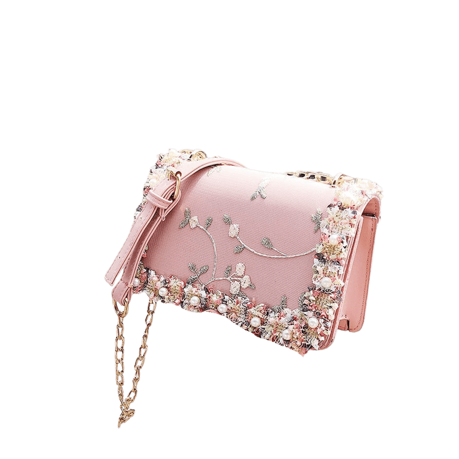 Pink ladies handbag with decorative flowers and pearls on the flap